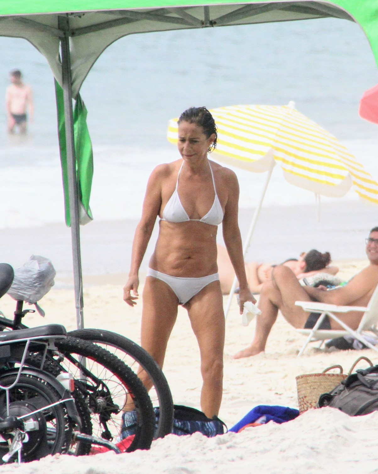 Foto de Andréa Beltrão andando na praia de biquíni branco