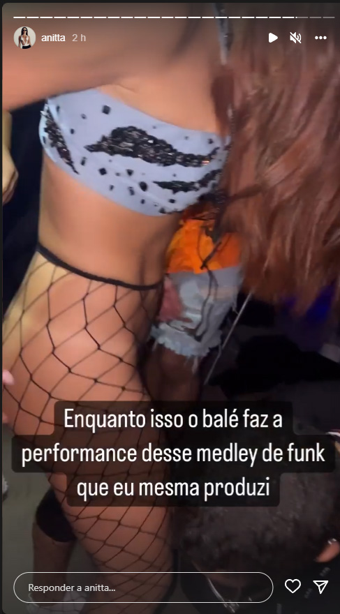 Anitta só de top e meia-calça com assistentes ajudando a trocar de roupa nos bastidores de show, com os dizeres: "Enquanto isso, o balé faz a performance desse medley de funk que eu mesma produzi"