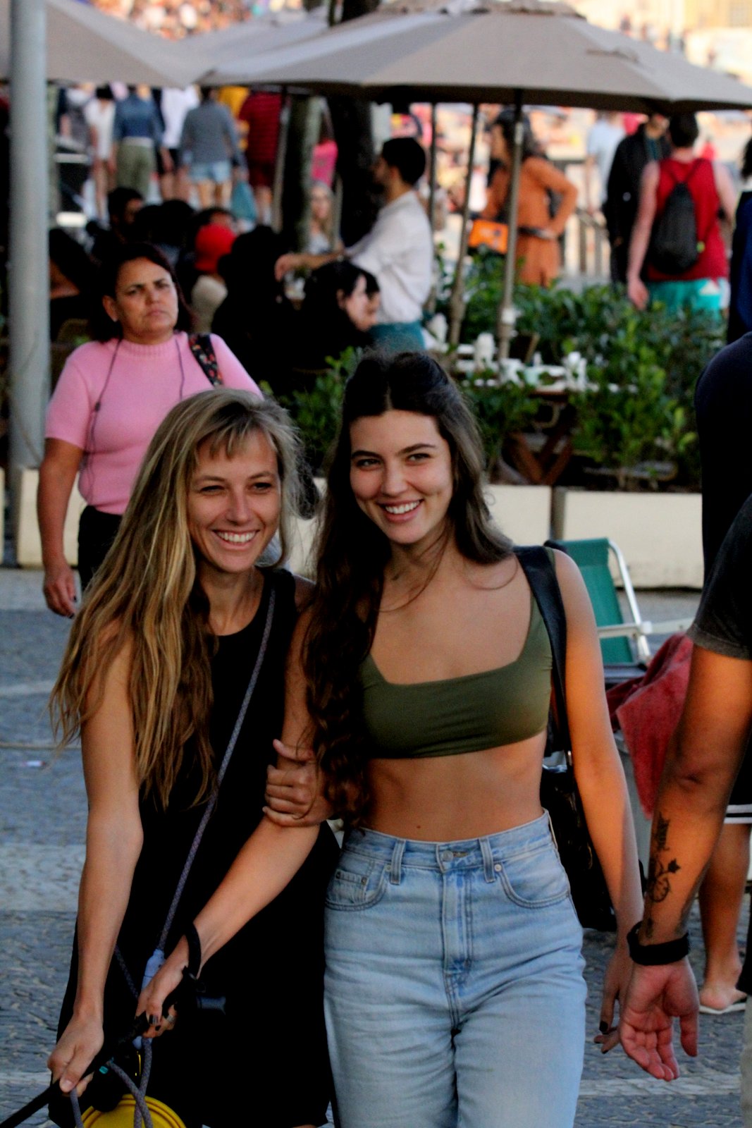 Foto de Alanis Guillen abraçada a mulher loira rindo na rua