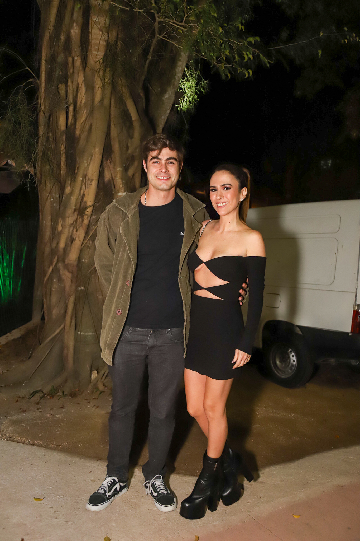 Foto de Tatá Werneck e Rafa Vitti posando sorridentes em ambiente noturno com roupa de festa