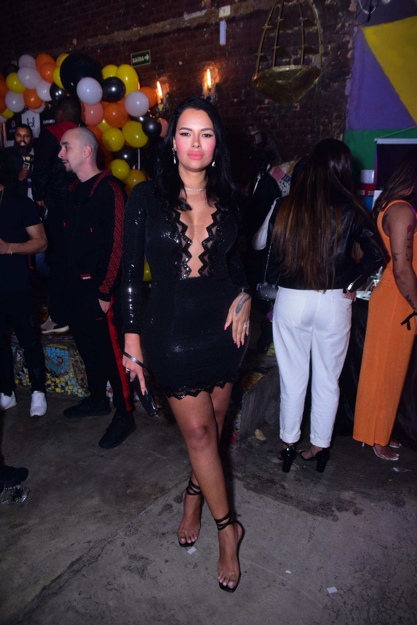 Foto de Ariadna Arantes com vestido preto e decotado em festa