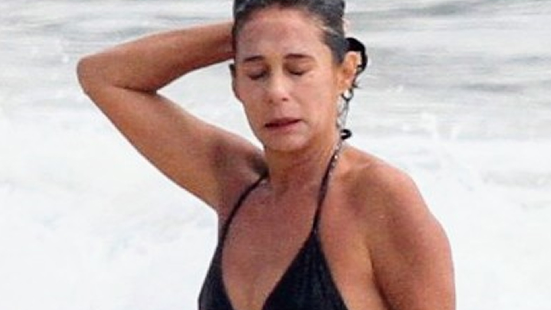 Aos 58 anos, Andréa Beltrão se refresca com abdômen sarado à mostra na praia