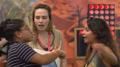 Três mulheres em uma discussão acalorada dentro de uma casa de reality show. Ao fundo, uma decoração temática de deserto.
