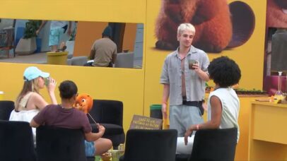 Participantes do BBB 23 conversam em sala com decoração amarela e imagem de um panda vermelho ao fundo.