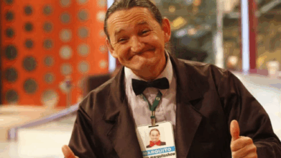 Marquito, do Programa do Ratinho, sorri e faz sinal de positivo com os polegares. Ele usa um terno e gravata borboleta.