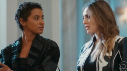 Duas mulheres em um ambiente interno, uma com cabelo curto e escuro, a outra com cabelo longo e claro, olhando uma para a outra em cena de confronto.