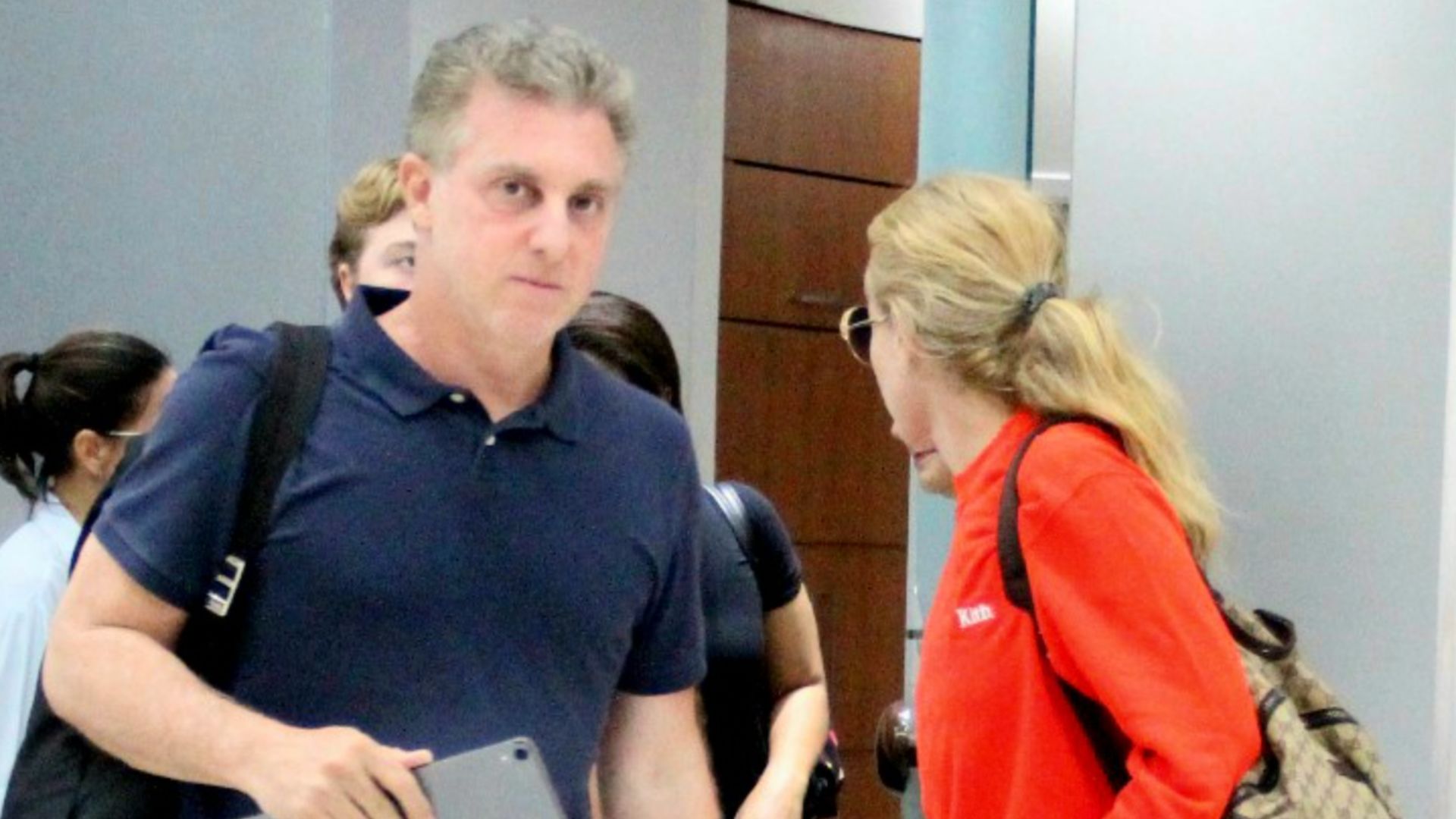 Com cara de poucos amigos, Huck é flagrado com Angélica e os três filhos em aeroporto