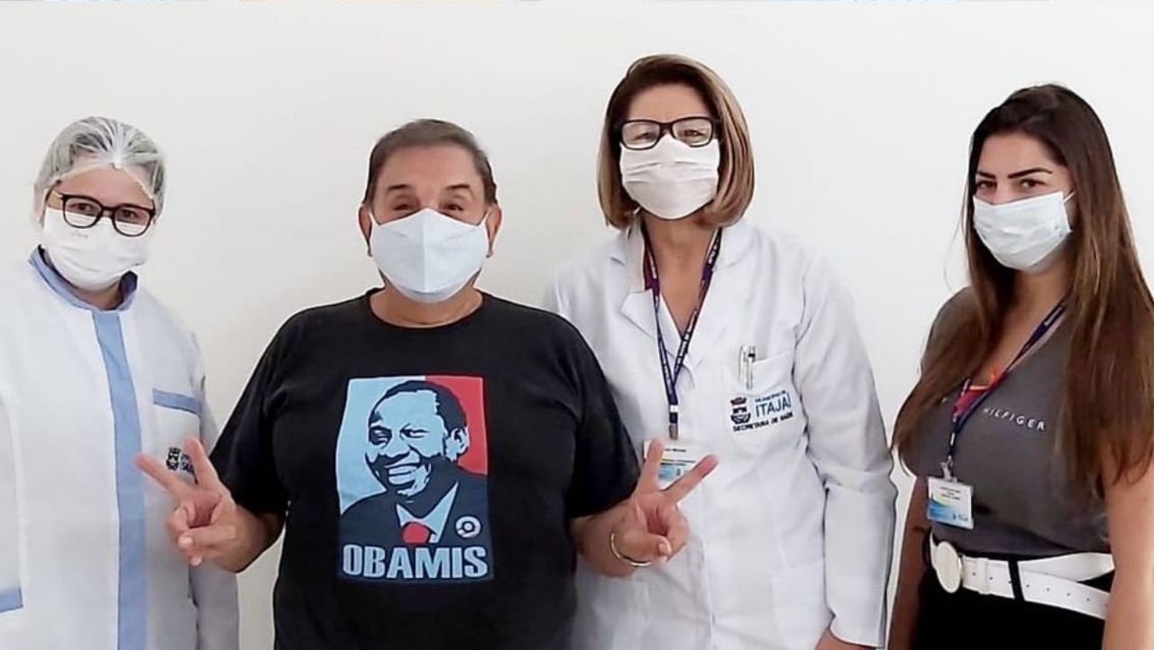 Usando camiseta com rosto de Mussum, Dedé Santana recebe vacina contra Covid-19