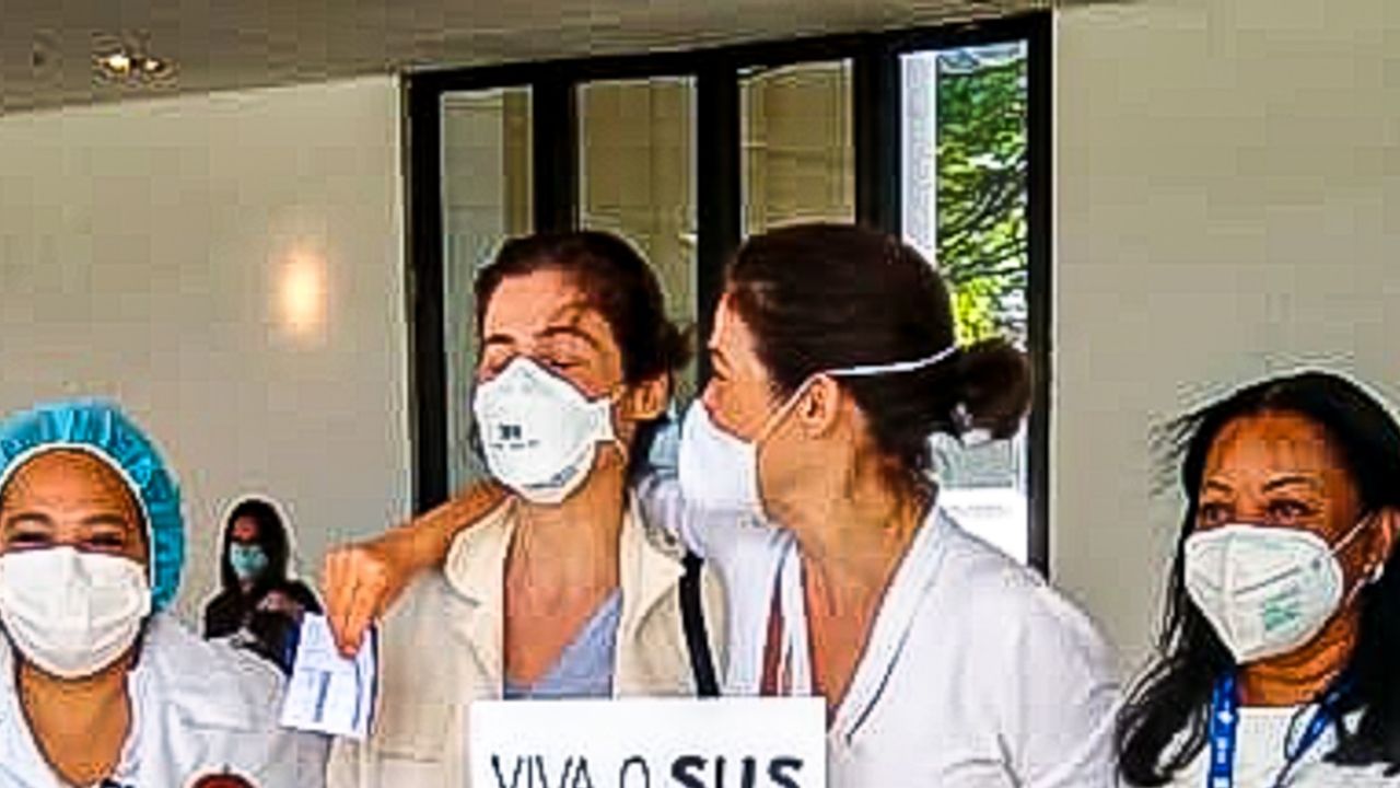 Comovida, Renata Vasconcellos se vacina ao lado da irmã gêmea e posa para fotos com cartaz de protesto