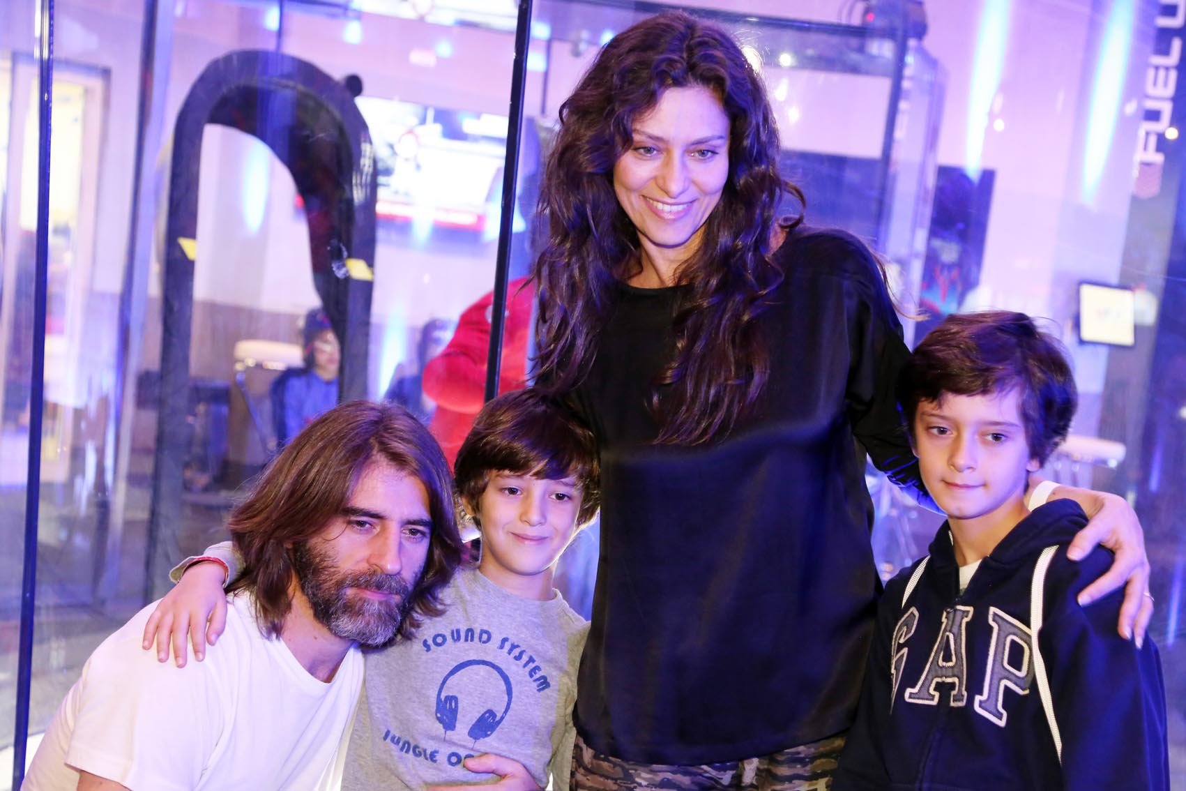 Maria Fernanda Cândido experimenta simulador de paraquedas com os filhos