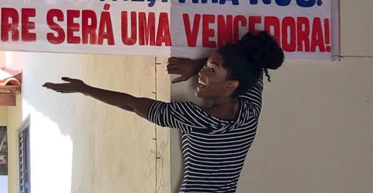 Erika Januza se emociona ao ganhar faixa de Parabéns da família ao chegar em Minas Gerais