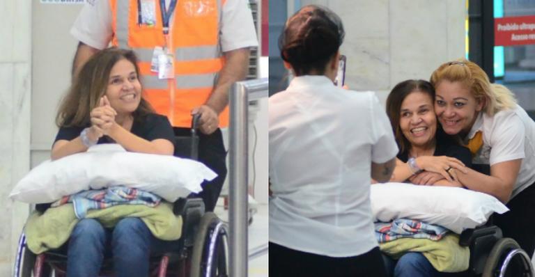 Claudia Rodrigues desembarca no Rio de Janeiro sorridente e posa com fãs
