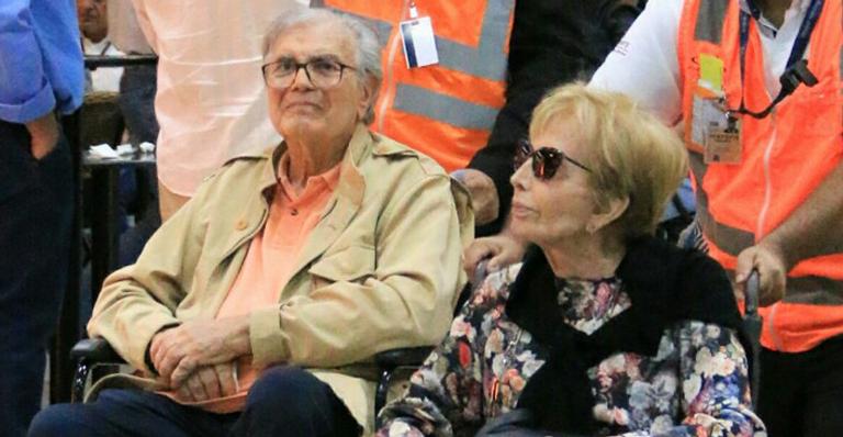 Tarcísio Meira e Gloria Menezes embarcam com a ajuda de cadeira de rodas