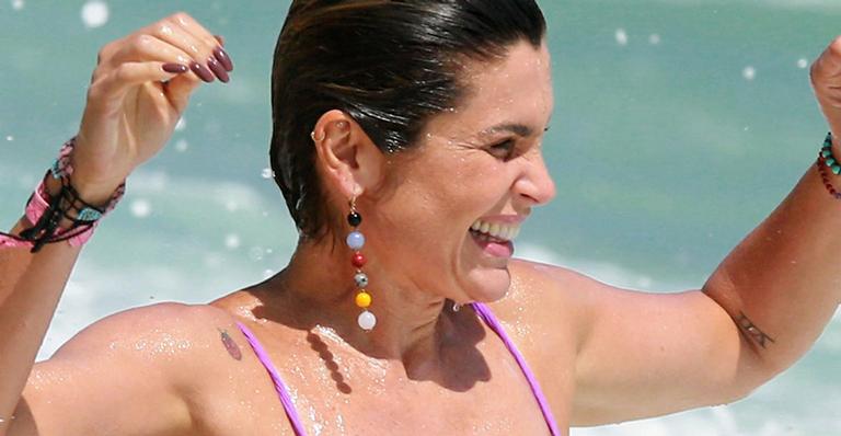 Flávia Alessandra é flagrada na praia com biquíni fio dental e corpo sem retoques
