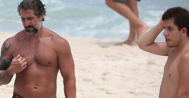 Com bermudinha minúscula, Marcos Mion exibe corpo musculoso ao ir à praia com a família